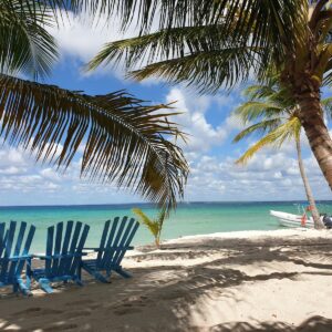 a couple of blue chairs sitting on top of a sandy beach