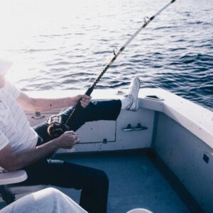 A man is fishing on a boat in the water