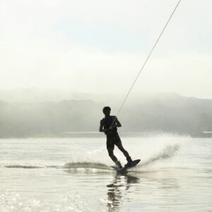 photo of man surfing on body of water and holding rope
